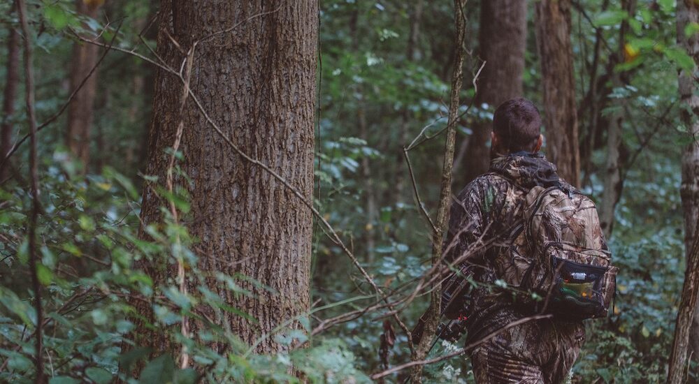 A man hunting in the woods using camouflage clothing
